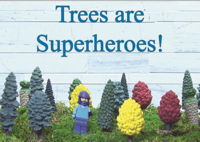 An image of a lego person with small toy size trees and words that read Trees are Superheroes.